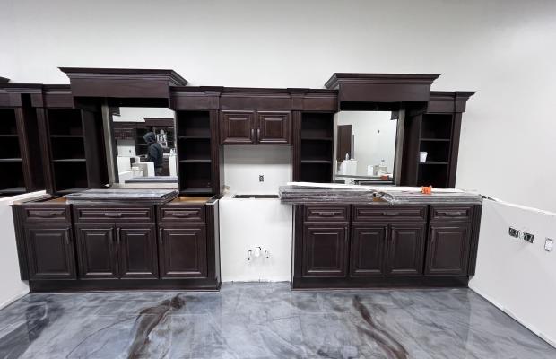 Espresso cabinet run with crown molding and open shelving bays over an epoxy floor