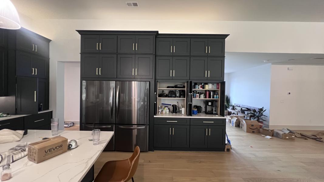 A finished dark Shaker kitchen with tall cabinets, a fridge surround and a stone island