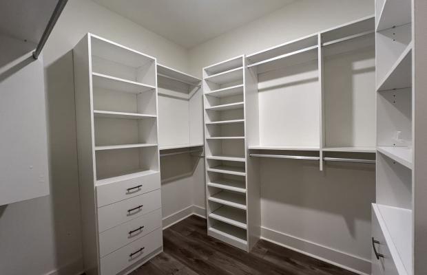 White walk-in closet system with adjustable shelving, hanging rods and a drawer bank