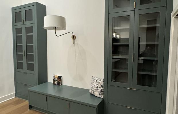 Sage green mudroom bench with glass-front cabinets either side