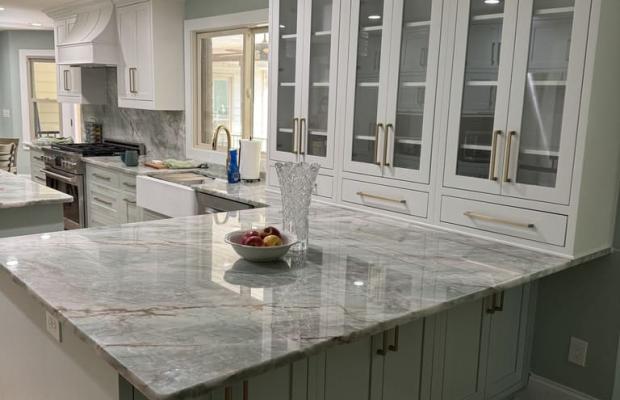 Sage green island run with glass-front upper cabinets over a stone counter