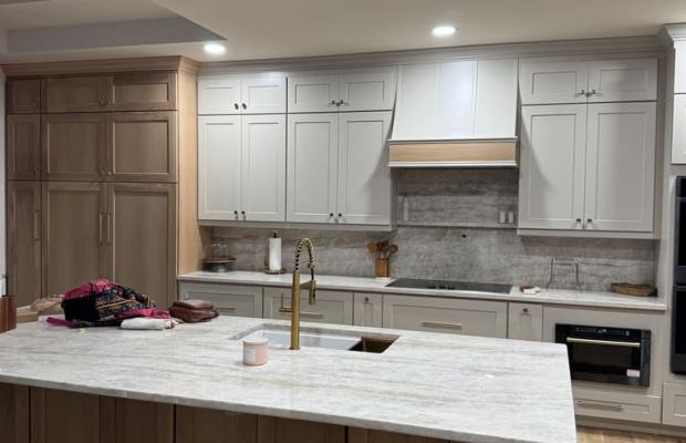 White upper cabinets with a wood range hood above a natural oak island
