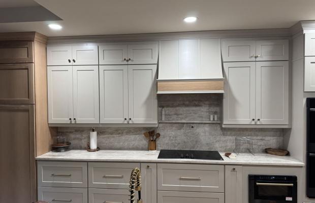 White shaker run with an induction cooktop under a wood-trimmed hood