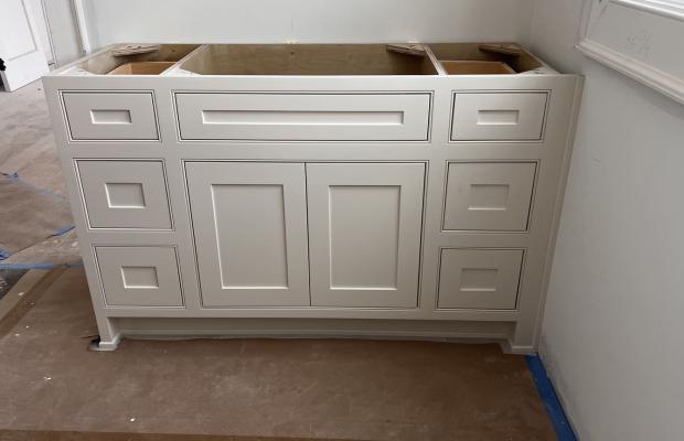 White vanity base cabinet set in a bathroom under construction, floor papered