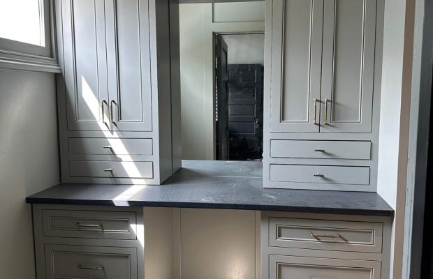 Built-in greige desk with drawer banks and a dark stone top between tall cabinets