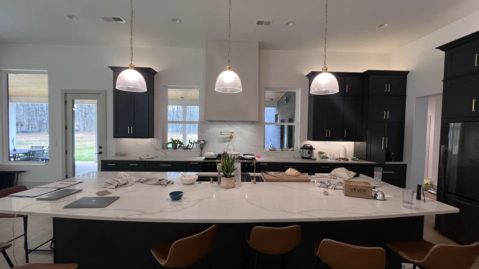Wide view of the charcoal shaker island with bar seating and three pendants