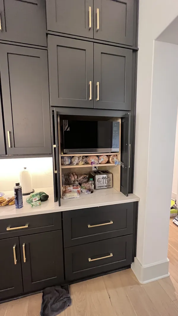 Tall charcoal cabinets with a built-in microwave and drawers below