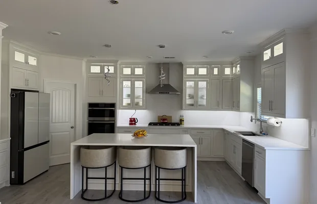 White kitchen with a waterfall island and three stools